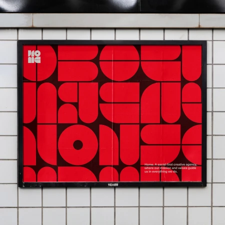 Red and black geometric poster in a black frame mounted on a white tiled wall in an indoor setting with visible text.