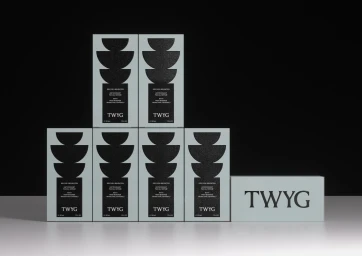 Seven light green TWYG skincare product boxes arranged in a stepped display against a split black and white studio background.