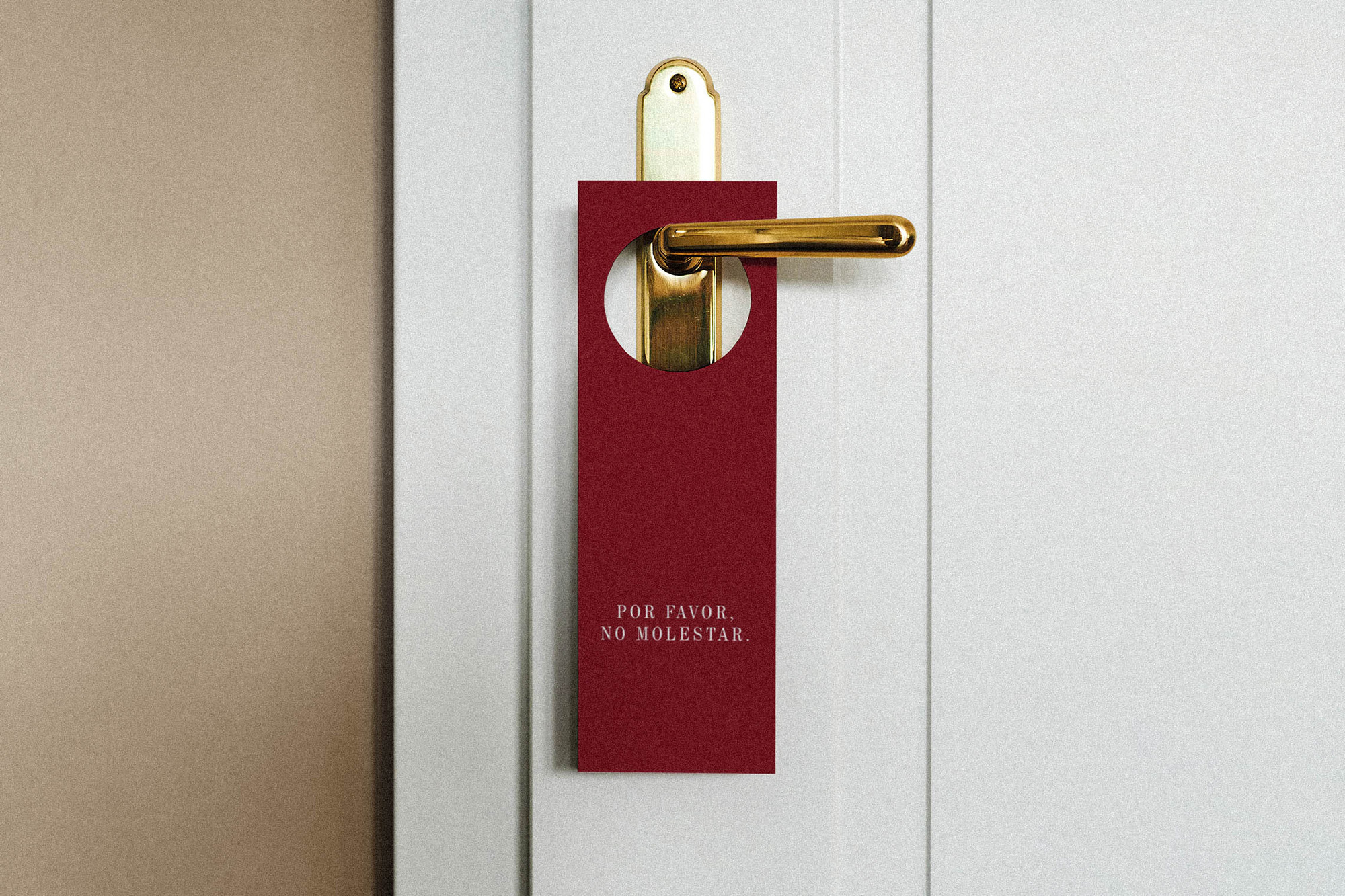 Close-up of a red 'Do Not Disturb' sign hanging on a gold door handle against a white door, conveying a sense of privacy.