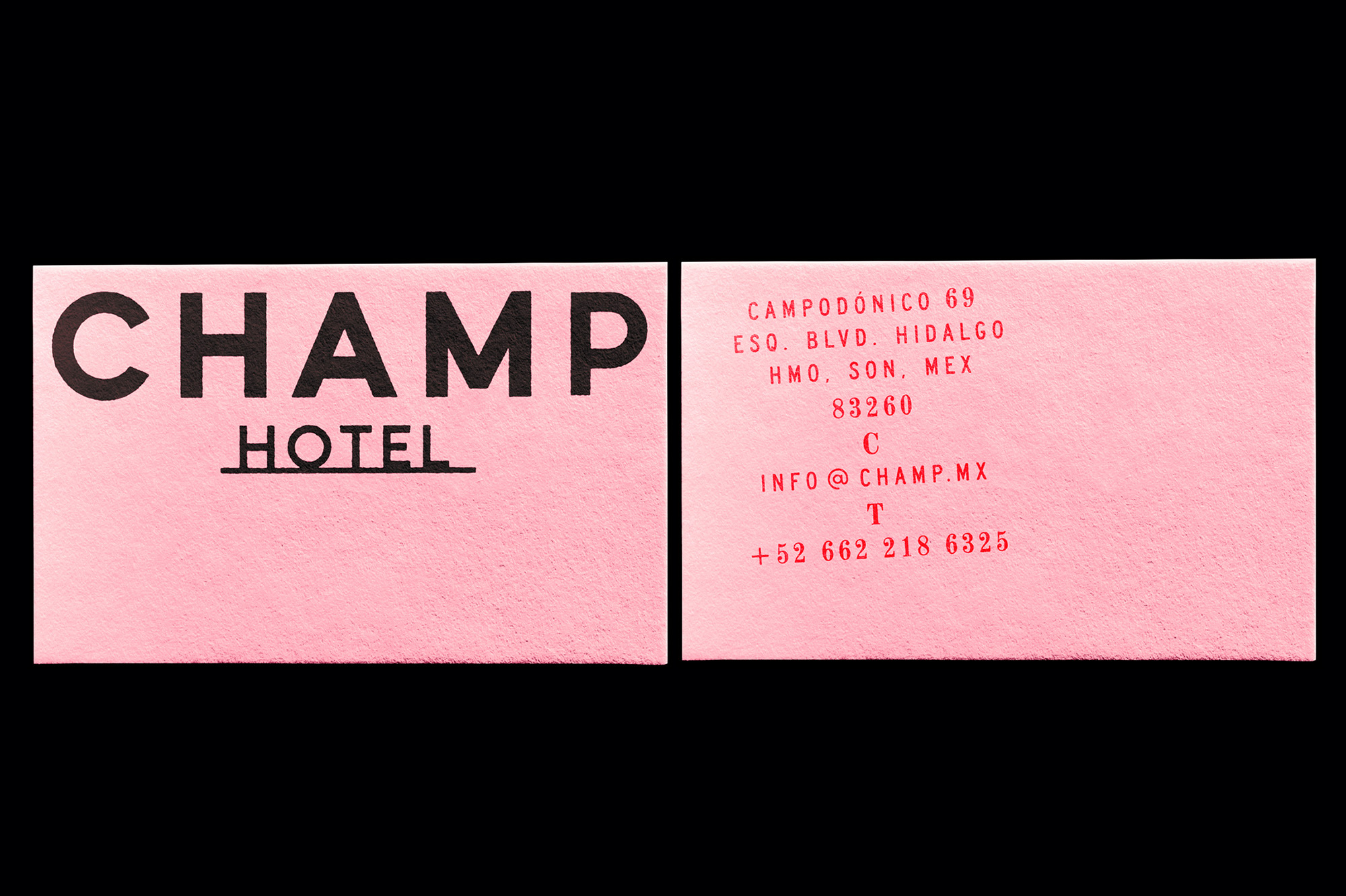 Two pink business cards for the CHAMP Hotel, featuring black lettering with the hotel's name, address, and contact information.