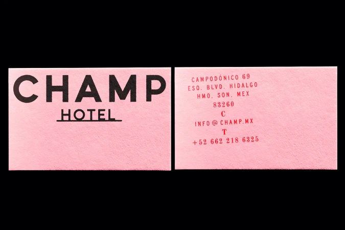 Two pink business cards for the CHAMP Hotel, featuring black lettering with the hotel's name, address, and contact information.