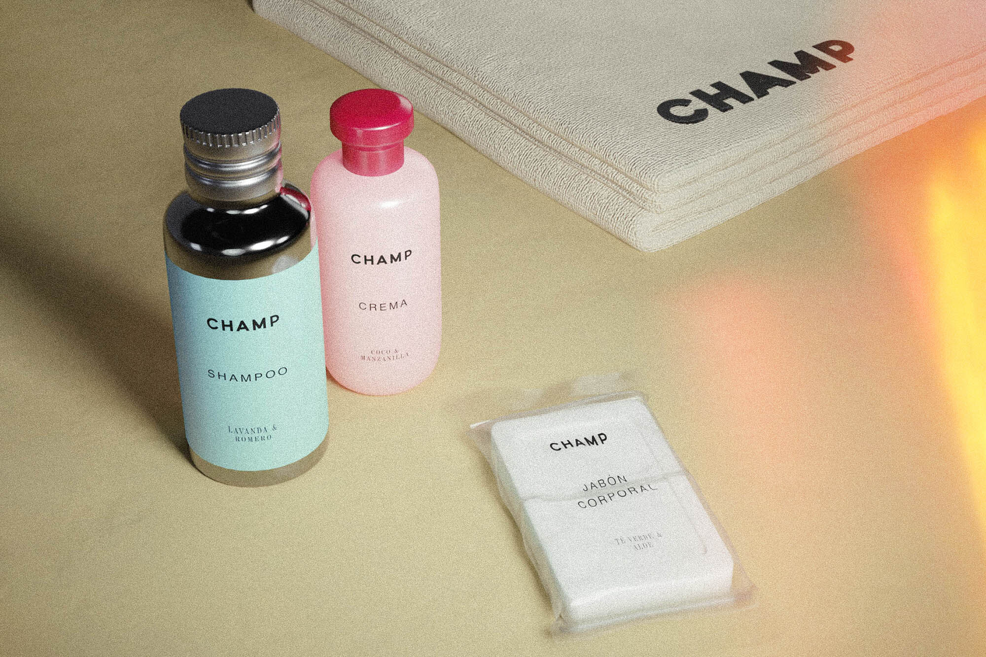 Still life of hotel toiletries including shampoo, body cream, and soap, arranged with a beige towel, with minimalist branding.