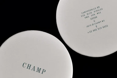 Close-up of two round white paper coasters with dark printed typography against a solid black background.