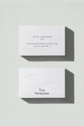 Two white business cards with embossed cloud designs and minimalist typography cast shadows on a textured grey surface