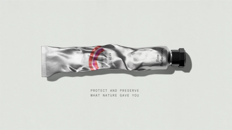 Crinkled silver metal tube of skincare cream with a black cap resting horizontally against a plain light grey background.