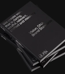Three stacked black brand standards books with silver debossed typography against a dark background
