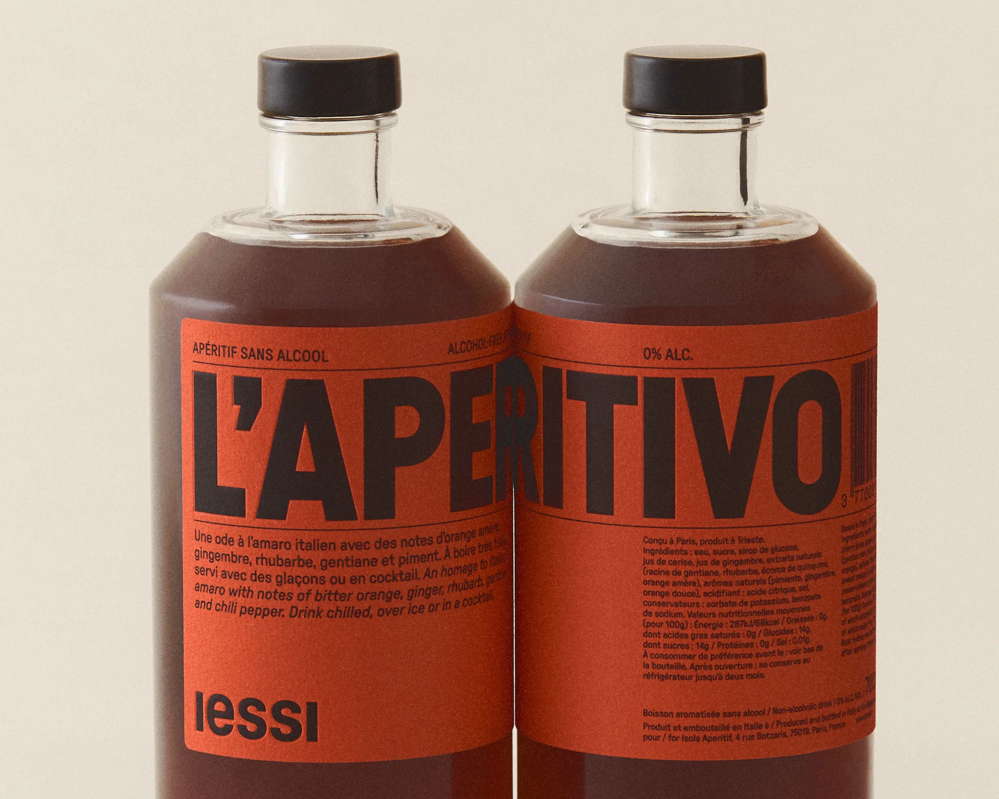 Two bottles of L'Aperitivo, a non-alcoholic aperitif, stand side-by-side. Each has a black cap and a red label with black text.