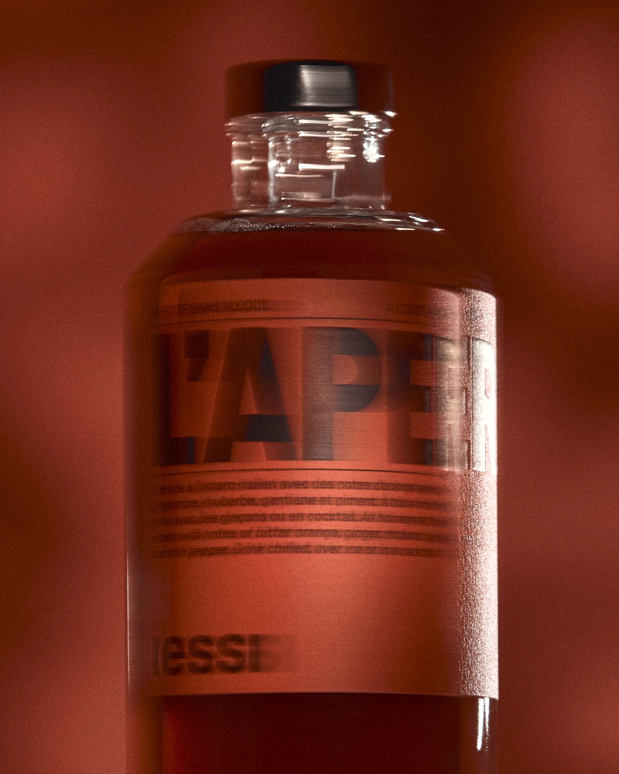 Close-up of a glass bottle with an orange liquid and label on a warm orange background.