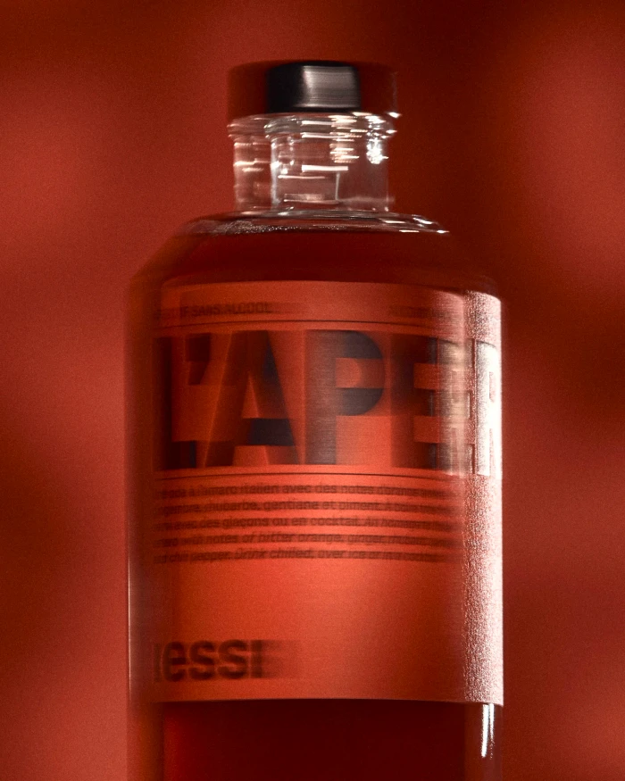 Close-up product shot of a glass beverage bottle with a red label against a warm red background.