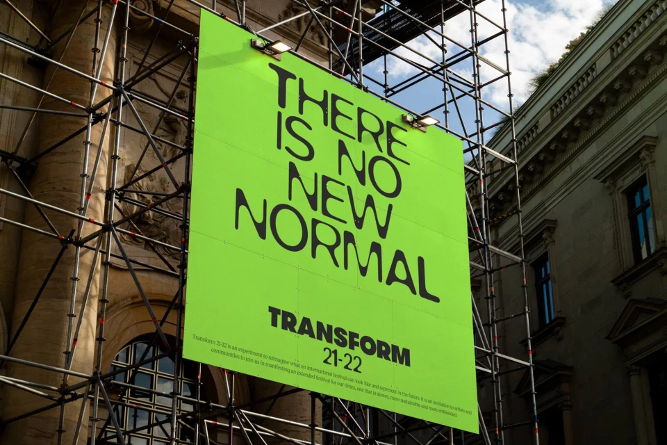 Large billboard displays the message 'There Is No New Normal' in bold, black font, mounted on scaffolding against a building and sky.