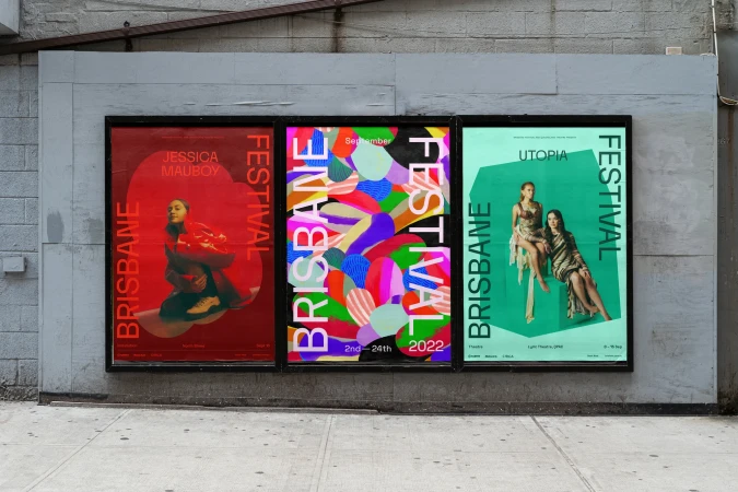 Three posters for the Brisbane Festival on a grey exterior wall, with red, blue, and green color schemes and models pictured.
