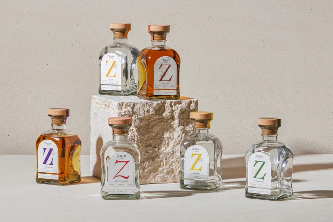 Multiple bottles of Ziegler spirits arranged on a stone surface against a neutral backdrop, showcasing various colored labels.