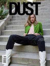 Coco Gordon Moore wearing a green jacket and white boots seated on outdoor concrete steps for Dust Magazine