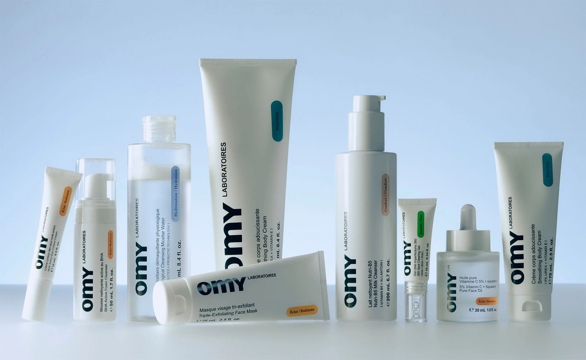 Collection of Omy Laboratoires skincare products in white bottles and tubes on a light backdrop, featuring cleansers and moisturizers.