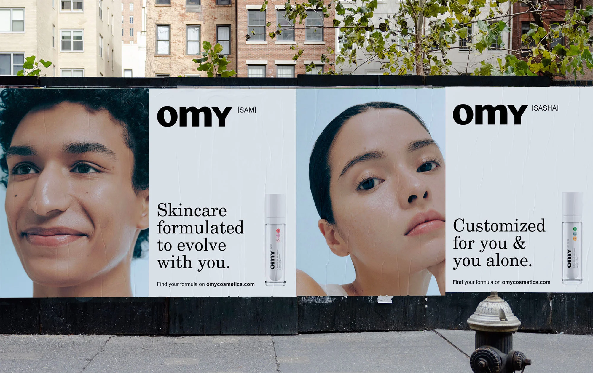 Omy brand identity billboards mounted on an urban street wall featuring close up portraits of two models with skincare products