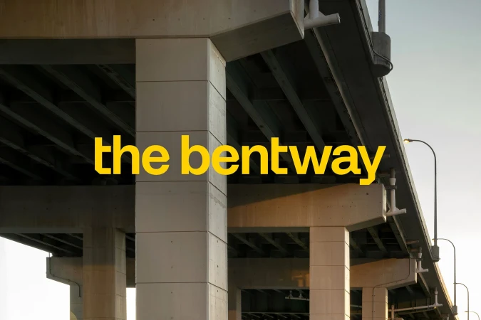 Concrete pillars supporting an elevated structure with 'the bentway' text overlayed, viewed from a low angle on a bright day.