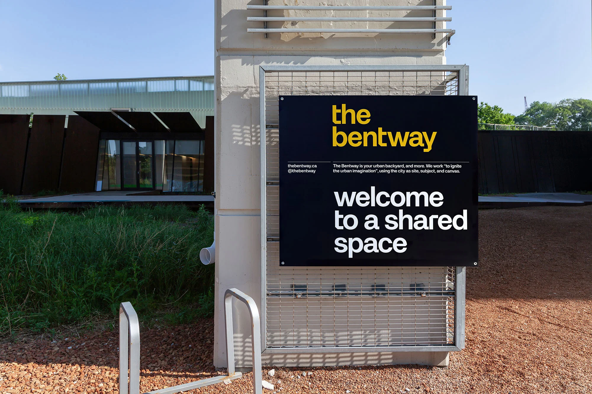 The Bentway signage on a concrete column with the words 'welcome to a shared space' in white block letters on a black background.