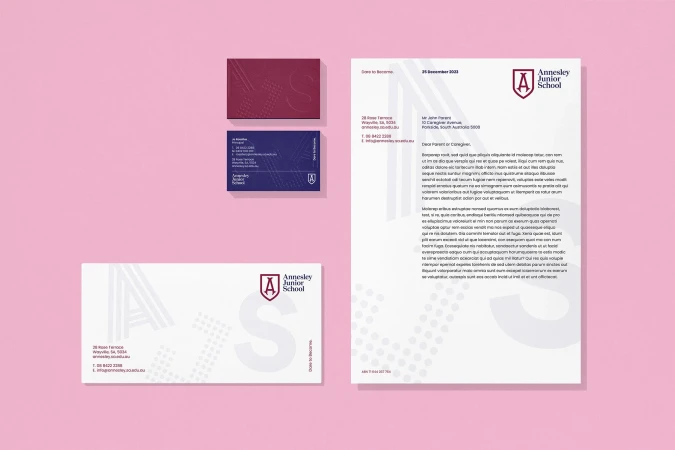 Promotional materials showcase the Annesley Junior School brand with letterhead, business cards, and an envelope on a pink background.