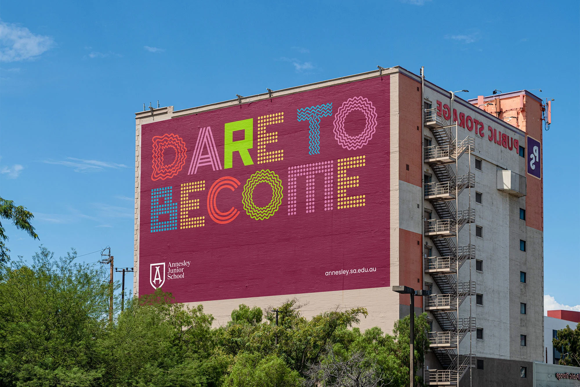 Exterior view of a building with the colorful painted words 'DARE TO BECOME' on its facade, adjacent to Public Storage signage.