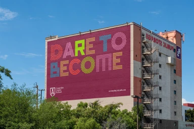 Large building mural with bold colorful typography reading Dare to Become for Annesley Junior School