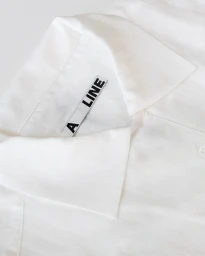 Close-up of a white shirt collar featuring the woven brand label A LINE against a clean light background