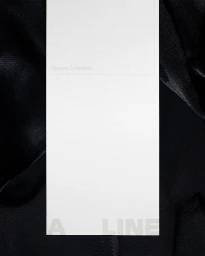 A vertical white paper label with the text A LINE resting on dark fabric