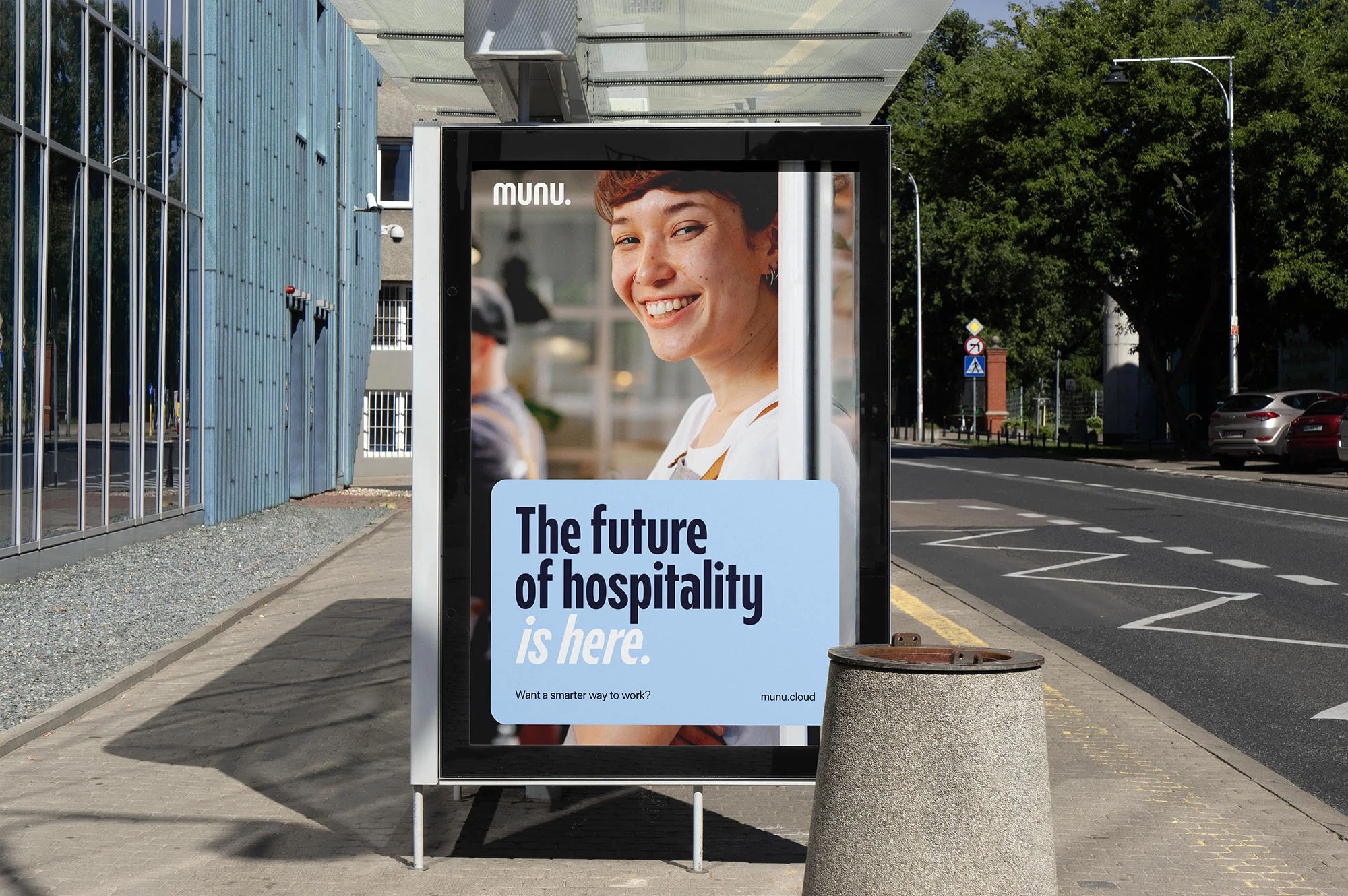 Outdoor shot of a bus stop advertisement featuring a smiling woman and the text 'The future of hospitality is here' for Munu Cloud.