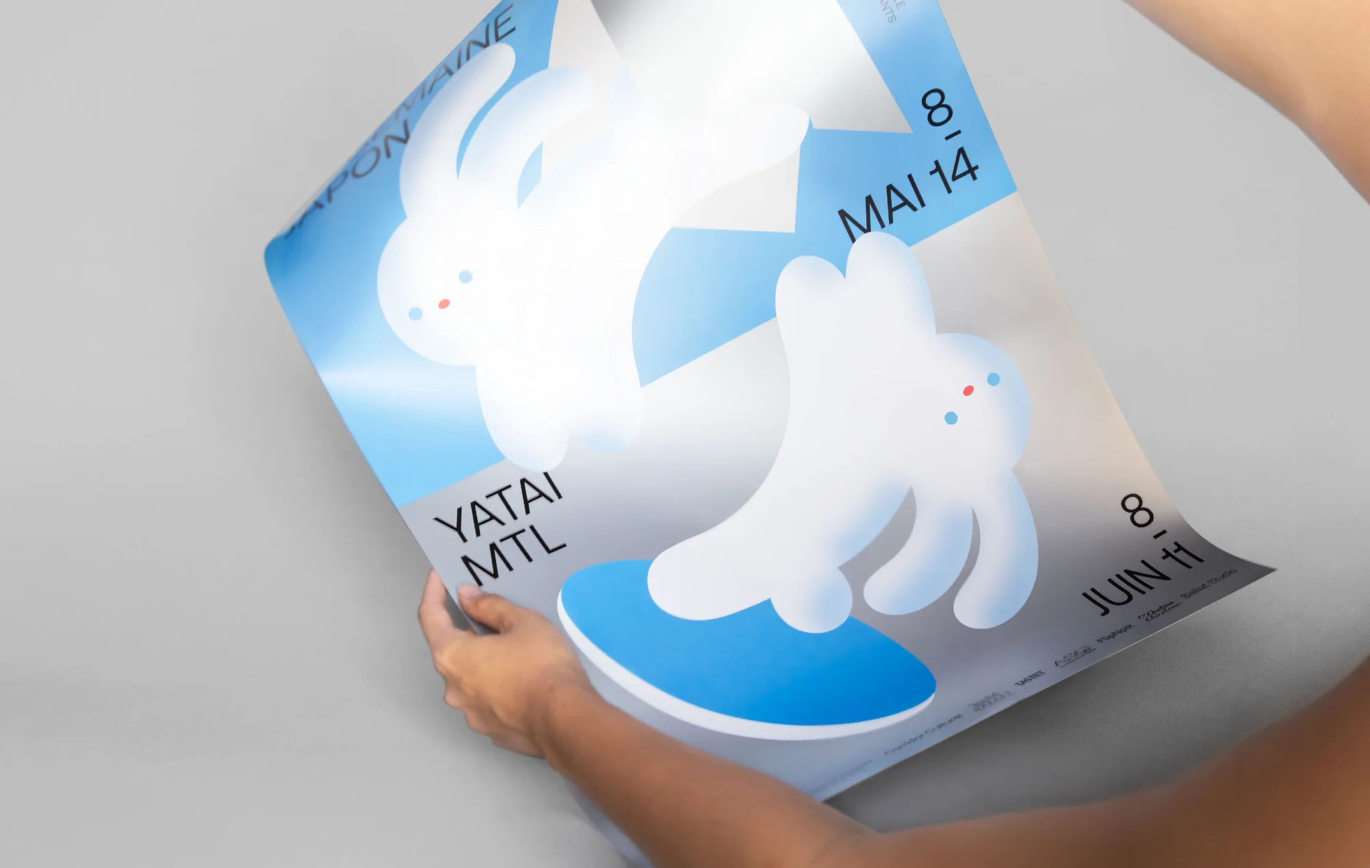 Hands holding an event poster with graphic bunny illustrations and blue accents against a neutral background.