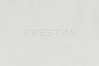 Debossed Preston brand typography on a clean light grey textured paper surface