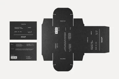 Flat-lay packaging design showing unfolding black soap carton templates with minimal white typography.