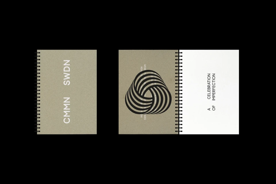 Three spiral-bound notebooks sit on a black surface. One notebook is open, revealing text on a white page. The other two are closed.