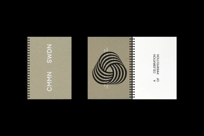 Three spiral-bound notebooks sit on a black surface. One notebook is open, revealing text on a white page. The other two are closed.