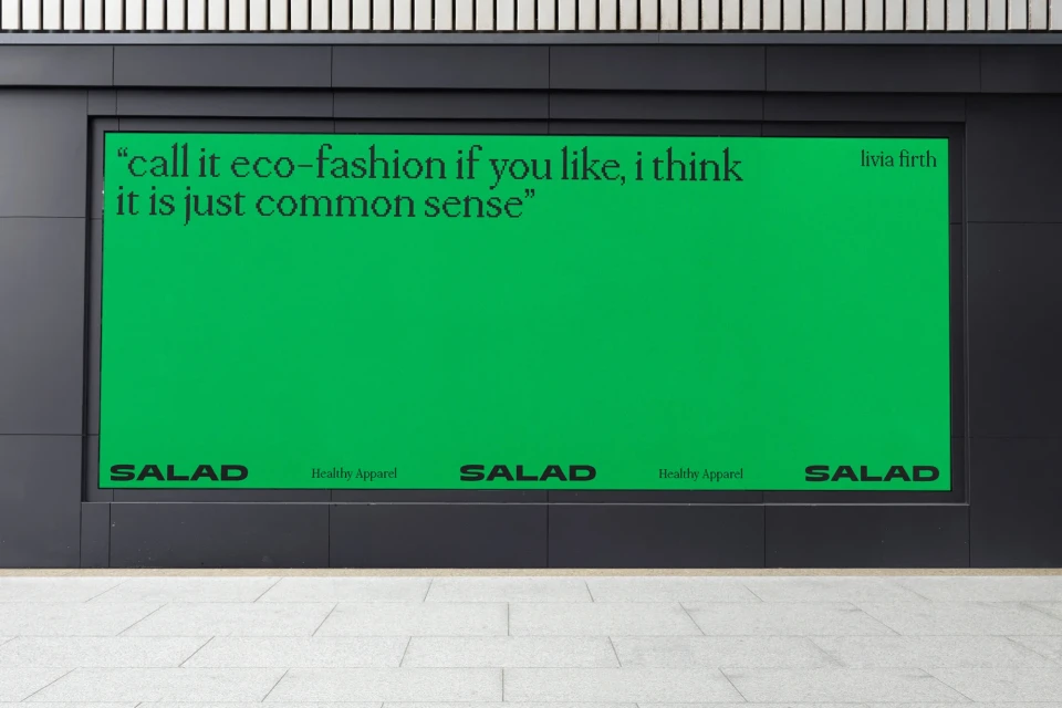 Outdoor advertising billboard with an eco-fashion quote by Livia Firth on a solid green background with SALAD Healthy Apparel branding.