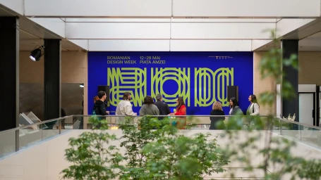 Group of people standing by a large blue banner with green graphic typography in an indoor multi-level building atrium