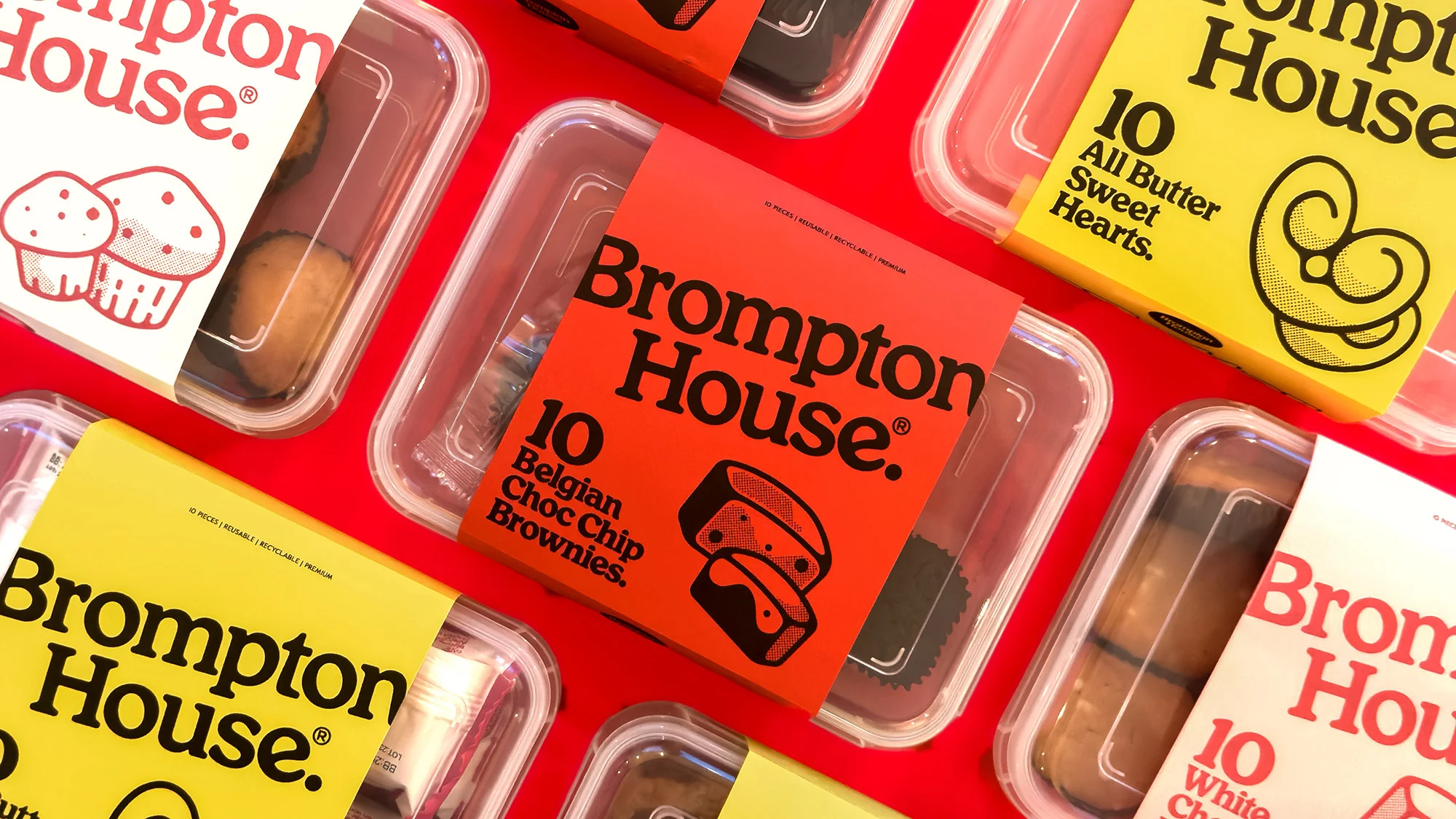 Overhead shot of Brompton House desserts in clear plastic containers with branded packaging on a bright red surface.