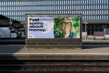 Taxfix brand billboard featuring graphic design text and a smiling woman on a platform by a train station