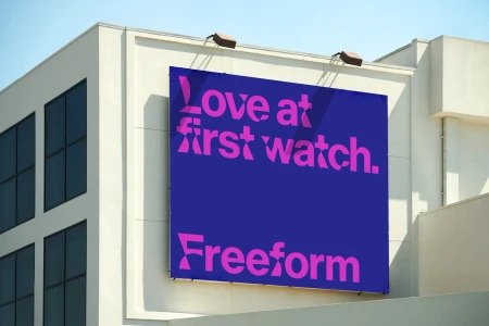 Large blue billboard with pink typographic text mounted on the exterior wall of a light beige commercial building.