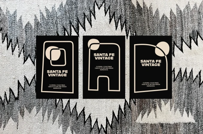 Three black rectangles featuring modern graphic designs and the text 'Santa Fe Vintage' rest on a woven textile with zigzag patterns.