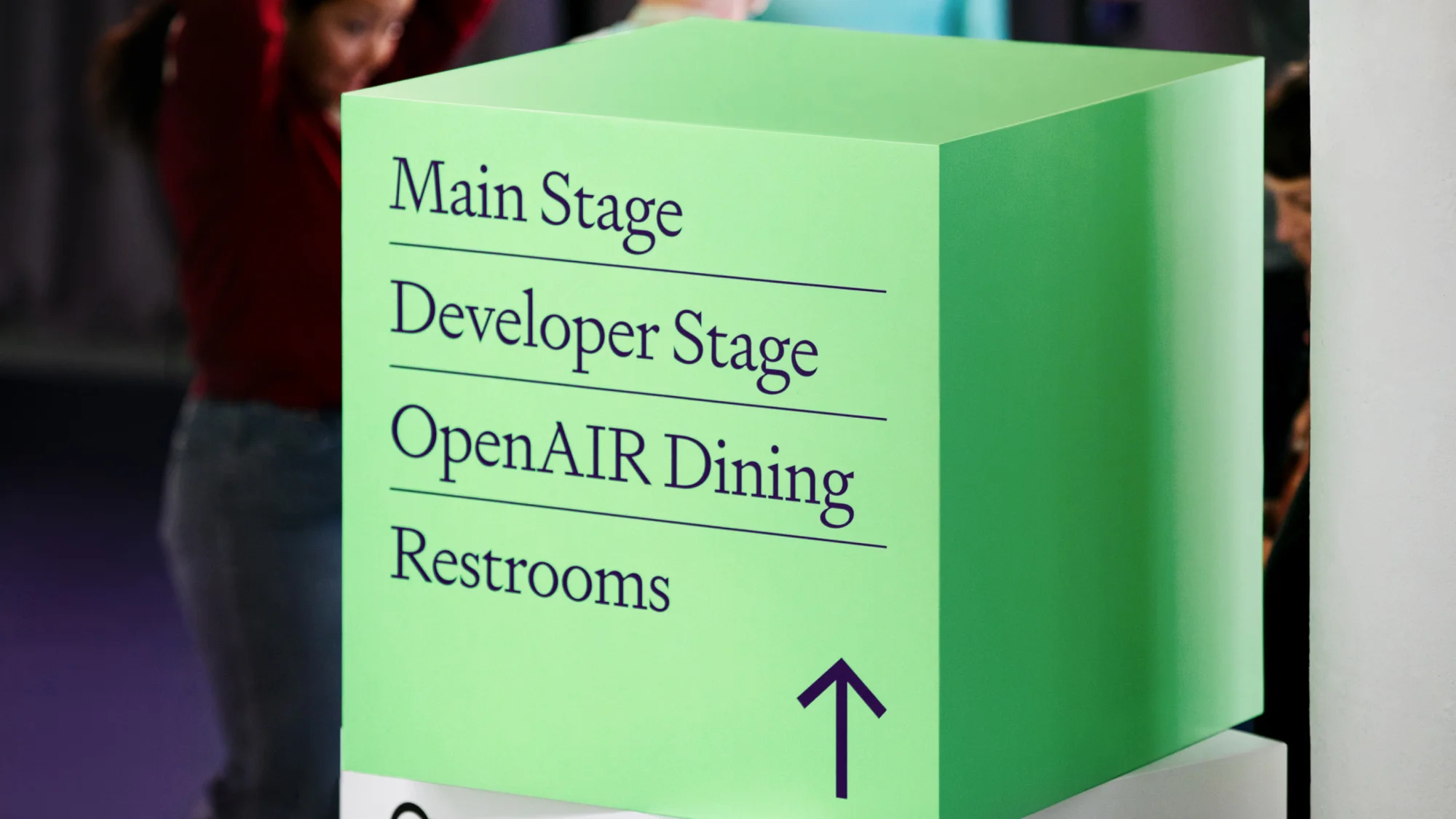 Directional sign with listings for Main Stage, Developer Stage, OpenAIR Dining and Restrooms in a modern indoor setting.
