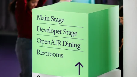 Green cube signage reading Main Stage, Developer Stage, OpenAIR Dining, and Restrooms for OpenAI brand identity.