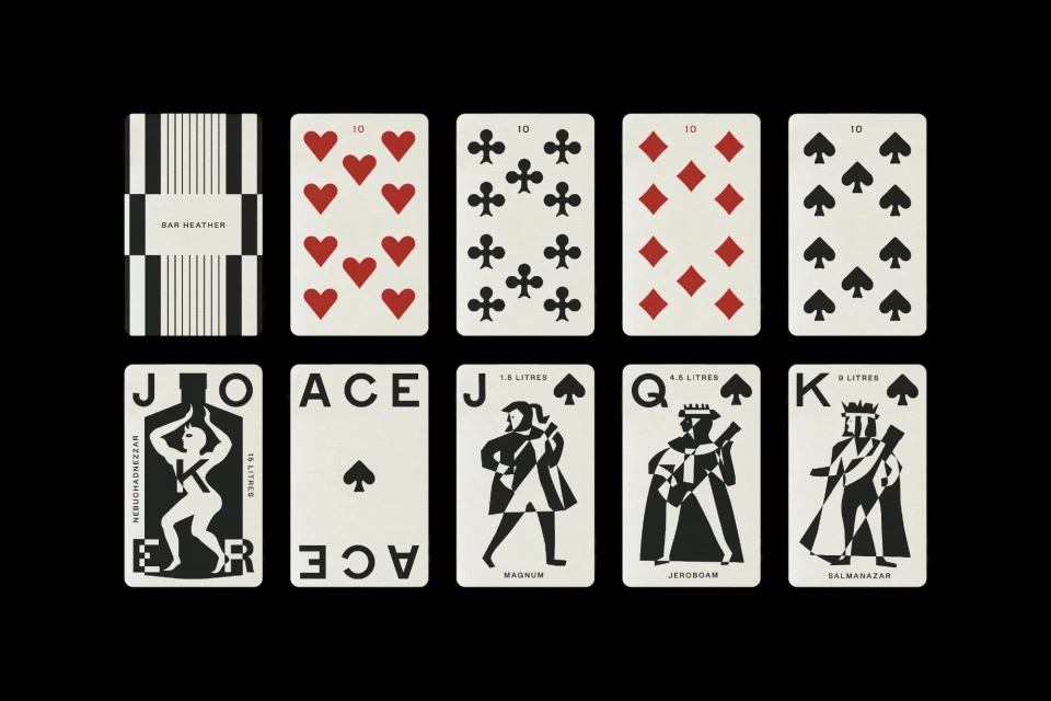 Arrangement of playing cards with graphic black and white designs and red suit symbols against a black background in a studio shot.