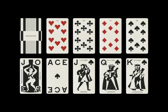 Arrangement of playing cards with graphic black and white designs and red suit symbols against a black background in a studio shot.