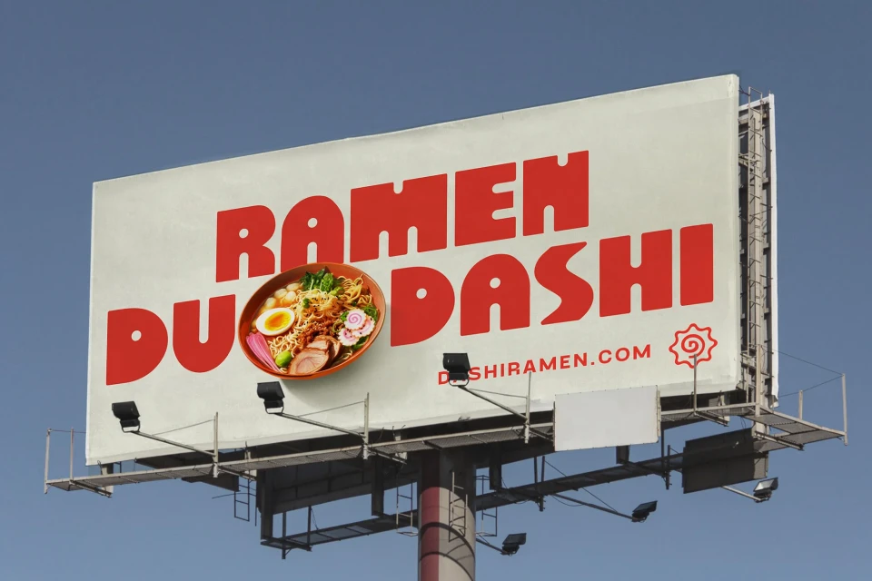 Billboard advertisement showcasing a bowl of ramen with noodles, egg, and vegetables against a blue sky. Text reads: Ramen Dashi.