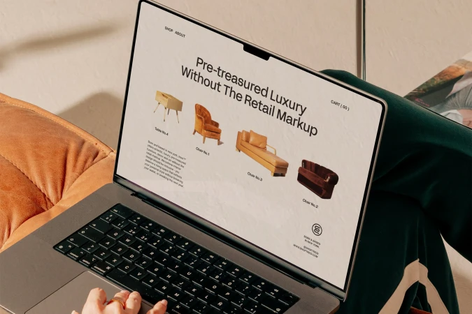 Close-up of a laptop screen displaying a furniture e-commerce website with vintage sofas and chairs, showcasing online shopping.