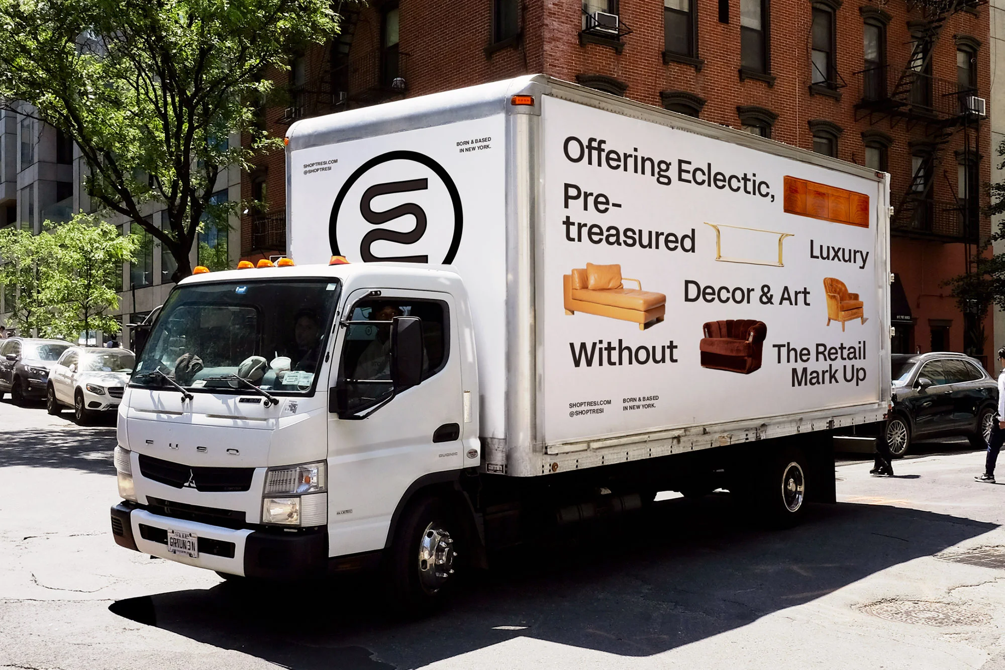 White commercial truck parked on city street with graphic advertisement featuring furniture and home decor, promoting eclectic, pre-treasured luxury.