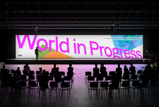Audience listens to presenter standing on stage in front of a large screen that reads, 'World in Progress' during presentation.