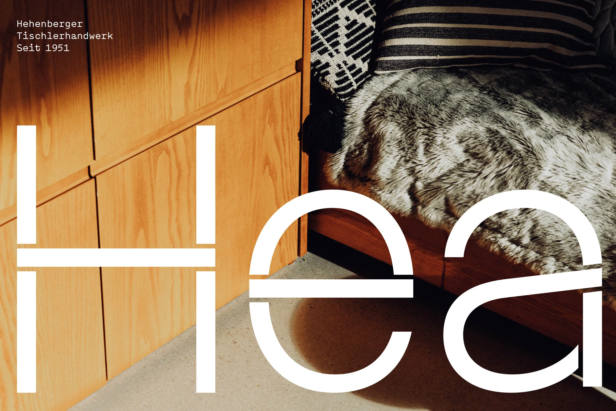 Interior shot showcases a wood cabinet with a cozy bed, featuring patterned pillows and a fur throw, alongside large white typography.