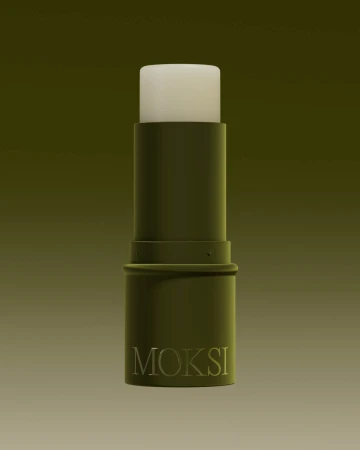 Close-up of an olive-green Moksi lip balm tube against a gradient background, showcasing minimalist design and neutral tones.