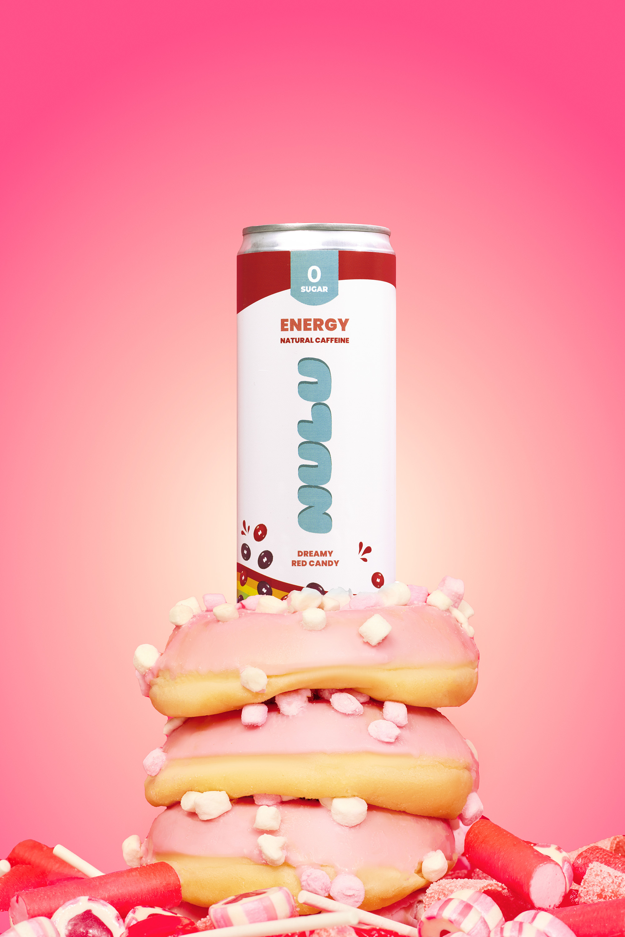 Stack of pink donuts topped with an energy drink can, surrounded by assorted pink and white candies against a gradient pink backdrop.