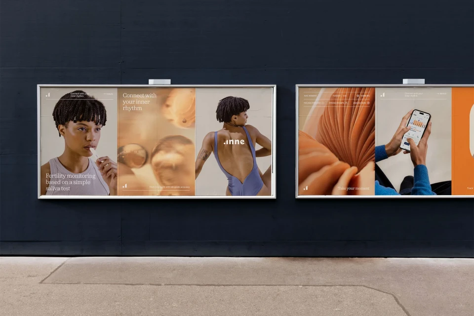 Two Inne fertility monitoring ads on a blue wall, featuring a woman and a hand holding a smartphone with tracking information.